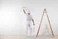 Rear view of painter man painting the wall, with paint roller an Royalty Free Stock Photo