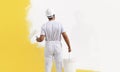 Rear view of painter man painting the wall, with paint roller and bucket, isolated on big empty copy space