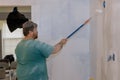 Rear view of painter paints the wall with a roller