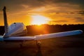 Rear view of a parked small plane on a sunset background. Silhouette of a private airplane landed at dusk.