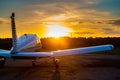 Rear view of a parked small plane on a sunset background. Silhouette of a private airplane landed at dusk.