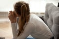 Rear view pensive thoughtful woman sitting on sofa, lost in thoughts