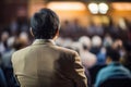 Rear view of people in audience at conference hall, speaker giving a talk at business event Royalty Free Stock Photo