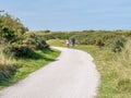 Rear view of people riding bikes on bicycle path in dunes of nature reserve Het Oerd on West Frisian island Ameland, Netherlands