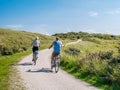 Rear view of people riding bikes on bicycle path in dunes of nature reserve Het Oerd on West Frisian island Ameland, Netherlands