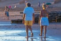 Rear view of people walking on the populated beach at sunset