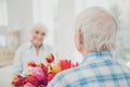 Rear view photo of two adorable aged people cute pair anniversary holiday surprise big red tulips bunch flat indoors