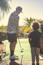 Rear view photo of two boys playing mini golf while on a fun family vacation together. Royalty Free Stock Photo