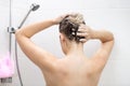 Rear view image of young brunette woman applying hair lotion while having shower Royalty Free Stock Photo