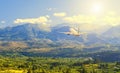 Rear view plane flying over beautiful valley , mountains, clouds and sun on background Royalty Free Stock Photo