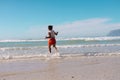 Rear view of playful african american girl running in sea against blue sky on sunny day Royalty Free Stock Photo