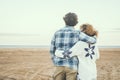 Rear view portrait of couple in love admiring the beach and ocean hugging with love. Romantic life in winter holiday vacation.