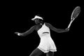 Rear view portrait of focused young woman, tennis player preparing to hit tennis ball against black studio background Royalty Free Stock Photo