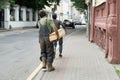 Rear view portrait of mature workman carrying long wooden board moving material in factory workshop