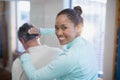 Rear view of portrait of smiling female therapist giving neck massaging to senior male patient Royalty Free Stock Photo