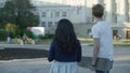 Rear view portrait of two students carrying walking and look at the building. Back view of a couple of students