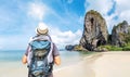 Rear view portrait of young man on holiday with hat and backpack looking at the sea and mountain,  enjoying travel and nature Royalty Free Stock Photo