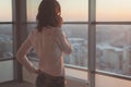 Rear view portrait of young worker speaking using cell phone, looking out the window. Female having business call, busy Royalty Free Stock Photo