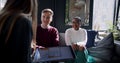 Rear view positive blonde young sales woman with tablet talks to happy multiethnic customers at loft trendy coffee shop.