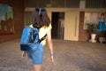 Rear view of a pretty little girl returning from school with a backpack in a yard