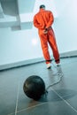 rear view of prisoner in orange uniform with weight tethered