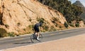 Rear view of a professional cyclist riding up on an empty road Royalty Free Stock Photo