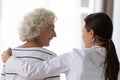 Caring nurse supporting hugging elderly woman clinic patient rear view Royalty Free Stock Photo