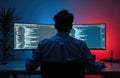 Rear view of programmer, data security expert working on computer in dark room. Displays show coding, software development Royalty Free Stock Photo
