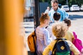 rear view of pupils entering school bus while teacher writing Royalty Free Stock Photo
