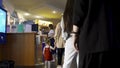 Rear view of queue of people buying the movie tickets at the movie theater hall. Media. Men, women, and a little girl