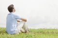 Rear view of relaxed young man sitting on grass against sky Royalty Free Stock Photo