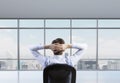 Rear view of the relaxing businessman is in a modern panoramic office. Royalty Free Stock Photo