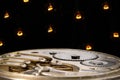 Rear view of retro pocket watch with clockwork. Vintage clock inside with gears on black background with glowing yellow