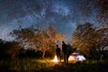 Rear view of romantic couple tourists standing at a campfire, beautiful night sky full of stars and milky way Royalty Free Stock Photo