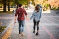 Rear view romantic couple walking in the autumn park holding hands Royalty Free Stock Photo