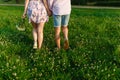 Rear view of a romantic man and woman stand on walk on field grass. Concept of lovely family holding hands. Young couple running t Royalty Free Stock Photo