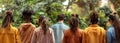 Rear view of a row of young friends in headphones listening to music in the park