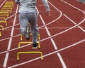 Rear view of runner running over mini hurdles on a track