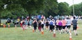 Rear view of runners following orange cones on the grass during 10K race in park