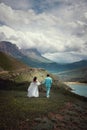 Rear view of running loving newlyweds holding hands, a bride in a wedding dress and a wife in a turquoise suit running Royalty Free Stock Photo