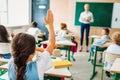 rear view of schoolgirl raising hand to answer teachers question Royalty Free Stock Photo