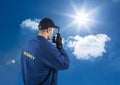 Rear view of security guard talking on walkie talkie against sky Royalty Free Stock Photo