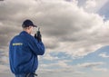 Rear view of security guard using radio against cloudy sky Royalty Free Stock Photo