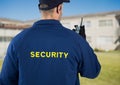 Rear view of security guard using radio against house Royalty Free Stock Photo