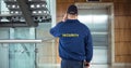 Rear view of security guard waiting for lift while standing in office building Royalty Free Stock Photo
