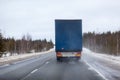 Rear view at semitrailer truck driving on slippery winter highway, northern forest route