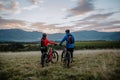 Rear view of senior couple bikers walking and pushing e-bikes outdoors in forest in autumn day. Royalty Free Stock Photo