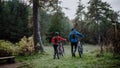 Rear view of senior couple bikers walking and pushing e-bikes outdoors in forest in autumn day. Royalty Free Stock Photo