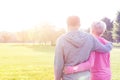 Rear view of senior couple in sportswear standing arms around in park Royalty Free Stock Photo