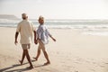 Rear View Of Senior Couple Walking Along Beach Hand In Hand Royalty Free Stock Photo